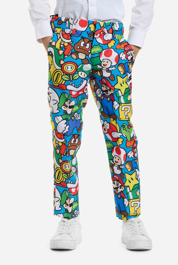 Afbeelding van kind dat een Super Mario all over print pak draagt, bestaande uit blazer, broek en stropdas. Hoofdkleur is blauw, maar er is ook geel, rood en wit.