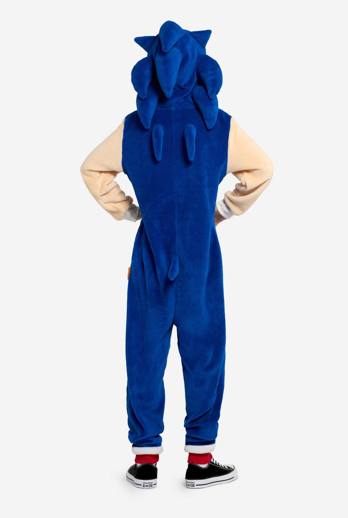 Een kind draagt ​​een blauw en beige Sonic the Hedgehog-thema kinderonesie van OppoSuits. De comfortabele onesie heeft een rits aan de voorkant en een capuchon die is ontworpen om te lijken op Sonics iconische gezicht, compleet met oren en een expressieve blik. Het blauwe lichaam van het pak contrasteert met de beige buik, wat Sonics look nabootst. Deze leuke, comfortabele en stijlvolle onesie is perfect voor loungen, themafeestjes en brengt nostalgische videogame-vibes naar elke gelegenheid.