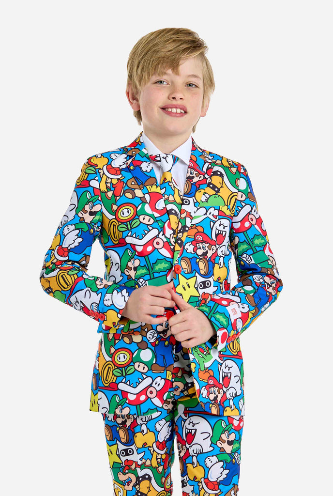 Afbeelding van tiener die een Super Mario all over print shirt draagt, bestaande uit blazer, broek en stropdas. Hoofdkleur is blauw, maar er is ook geel, rood en wit.