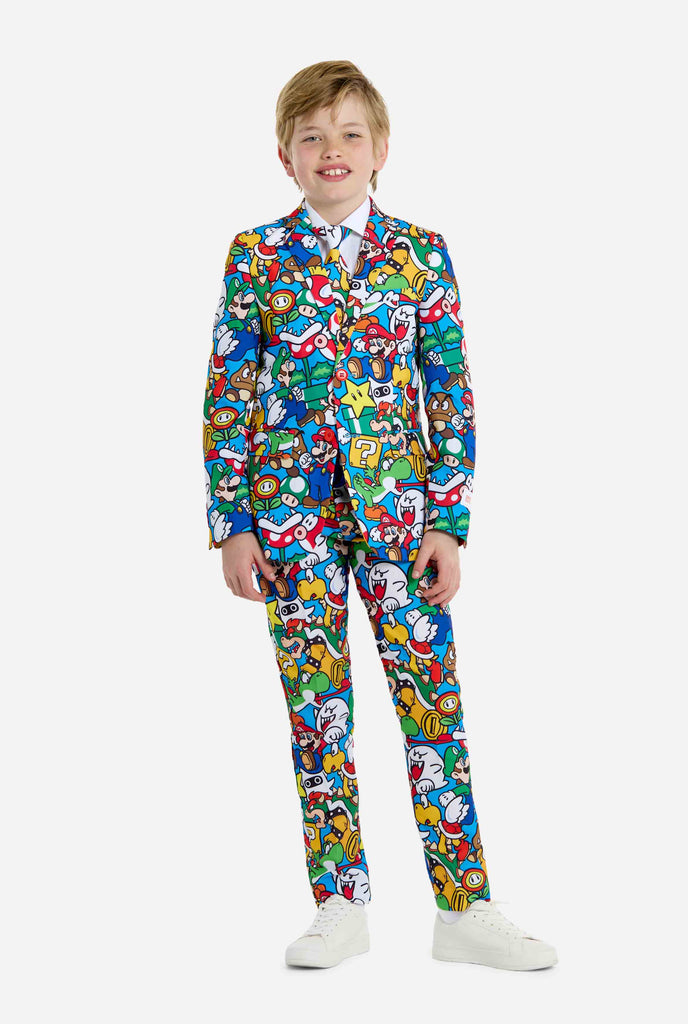 Afbeelding van tiener die een Super Mario all over print shirt draagt, bestaande uit blazer, broek en stropdas. Hoofdkleur is blauw, maar er is ook geel, rood en wit.