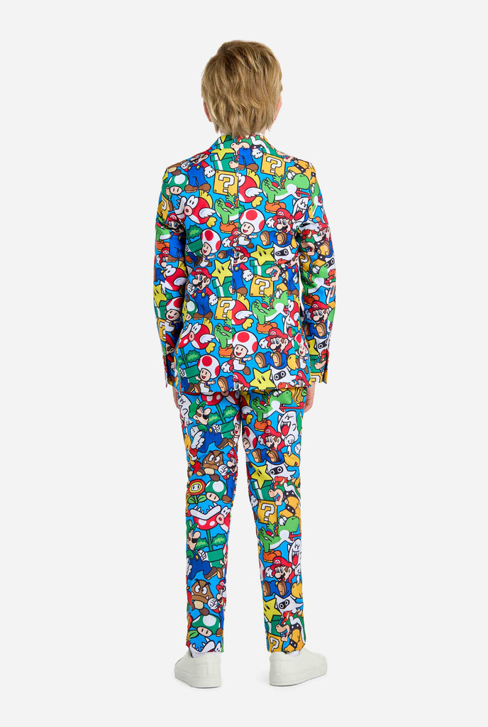 Afbeelding van tiener die een Super Mario all over print shirt draagt, bestaande uit blazer, broek en stropdas. Hoofdkleur is blauw, maar er is ook geel, rood en wit.