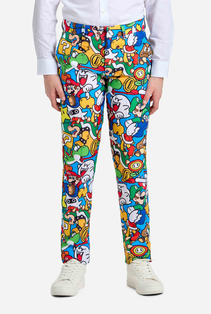 Afbeelding van tiener die een Super Mario all over print shirt draagt, bestaande uit blazer, broek en stropdas. Hoofdkleur is blauw, maar er is ook geel, rood en wit.