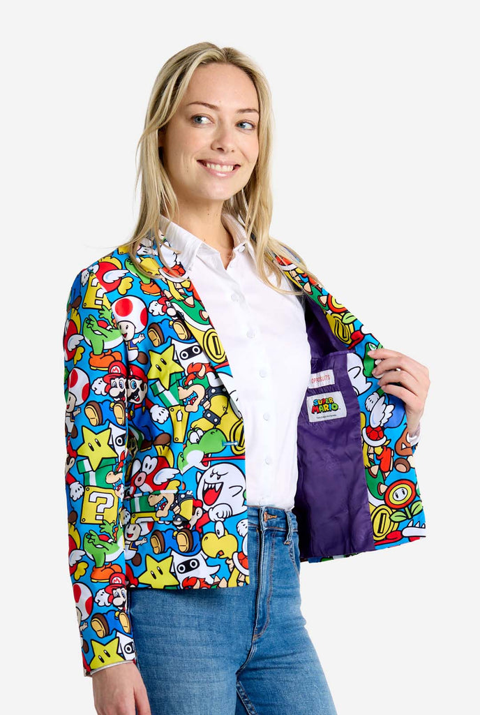 Vrouw draagt ​​een all-over print Super Mario blazer met iconische Super Mario karakters. De basis is lichtblauw, maar er is ook geel, rood en wit.