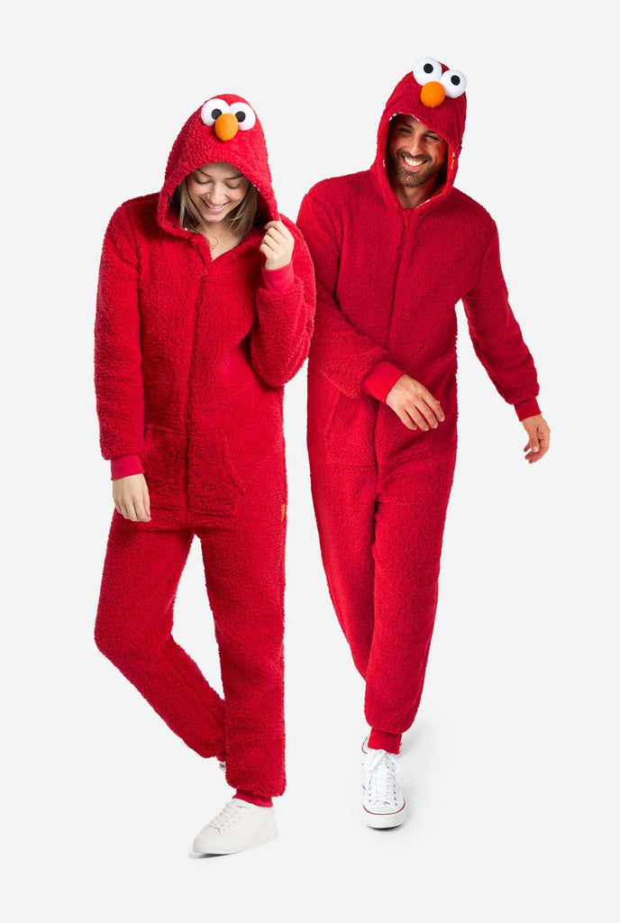 Een man en een vrouw zijn gekleed in een rode Elmo-onesie. Het algehele ontwerp imiteert de look van het Sesame Street-personage Elmo. De achtergrond is effen, waardoor de nadruk op het kostuum ligt. Full body image.