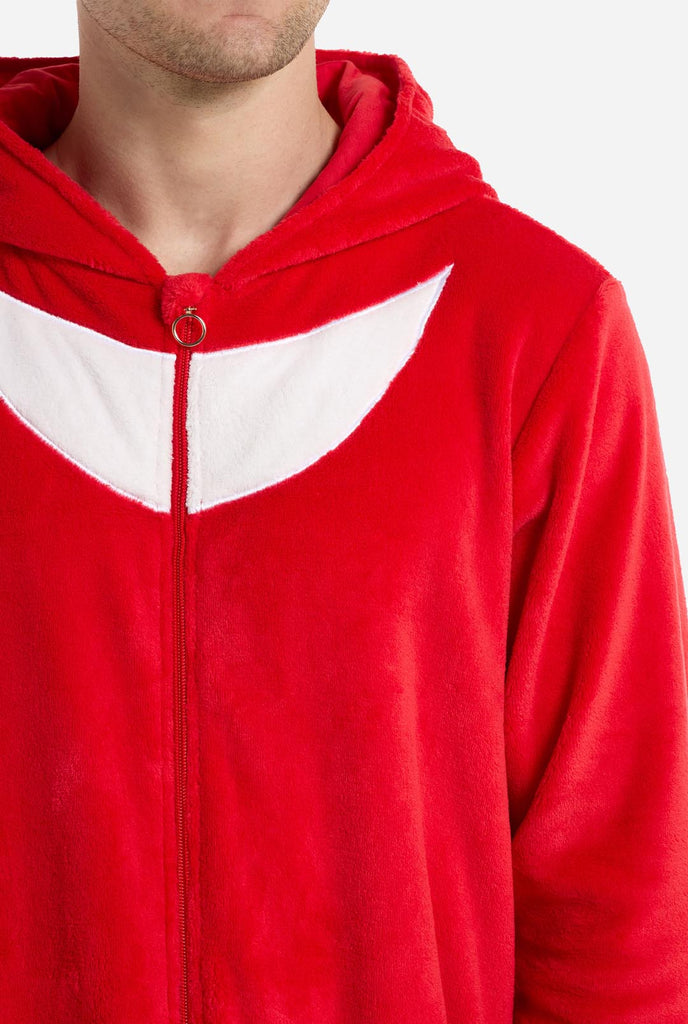 Een man draagt ​​een felrode onesie voor volwassenen met Knuckles the Echidna-thema van OppoSuits. De leuke en knusse onesie heeft een ritssluiting aan de voorkant en een vaste capuchon die lijkt op het gezicht van Knuckles, compleet met expressieve ogen en slappe dreadlocks. Het pak is voornamelijk rood, met een wit halvemaanvormig patroon op de borst, wat de iconische look van Knuckles uit de videogameserie Sonic the Hedgehog weerspiegelt. Close up.