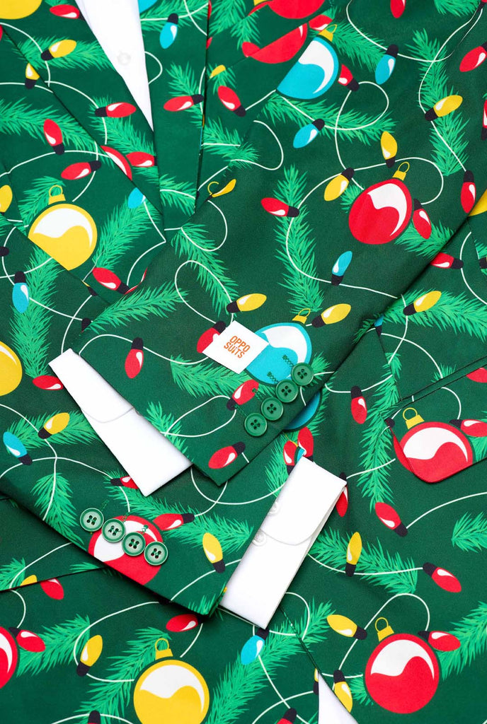 Man wearing green Christmas blazer for men with decorated Christmas tree print. Close up with white shirt.