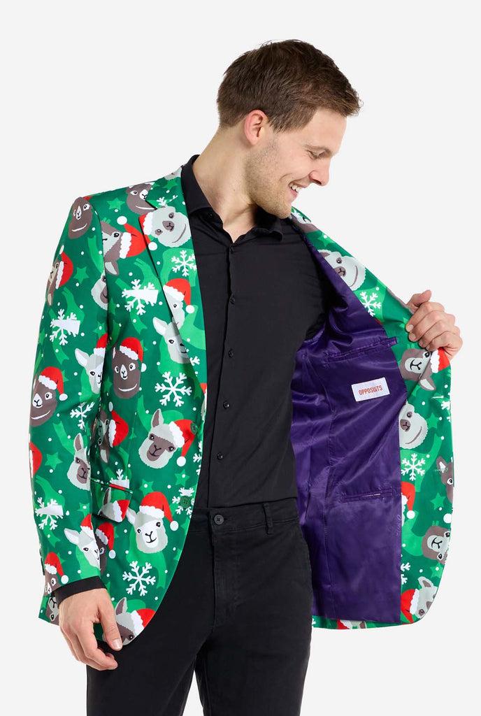 Man wearing green Christmas blazer for men with Christmas llamas. Man also wearing a black pants and black men's shirt. Showing purple inside of jacket.