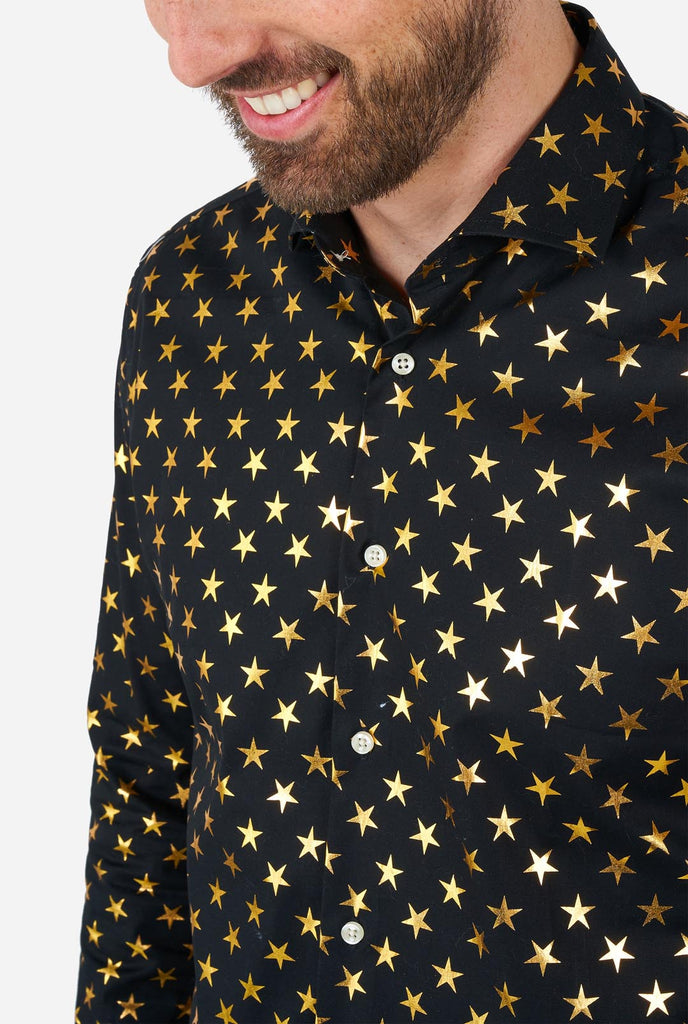 Deze afbeelding toont een stijlvol herenoverhemd van OppoSuits, ontworpen met een zwarte basis versierd met een opvallend gouden sterrenpatroon. Het overhemd heeft een strakke en eigentijdse pasvorm, perfect voor degenen die een vleugje flair aan hun garderobe willen toevoegen. Ideaal voor feestelijke gelegenheden, feestjes of om een ​​gedurfde statement te maken, combineert dit overhemd elegantie met een unieke, speelse twist. Borst close-up.