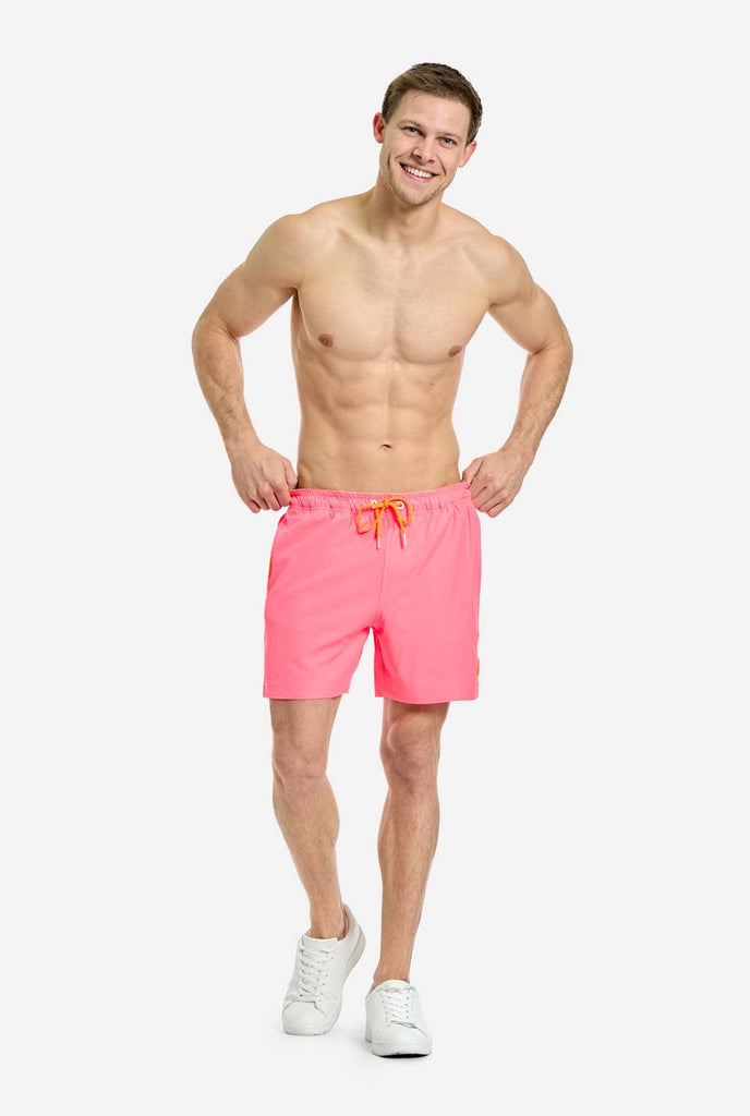 Man wearing Neon Pink Power swim trunks for men