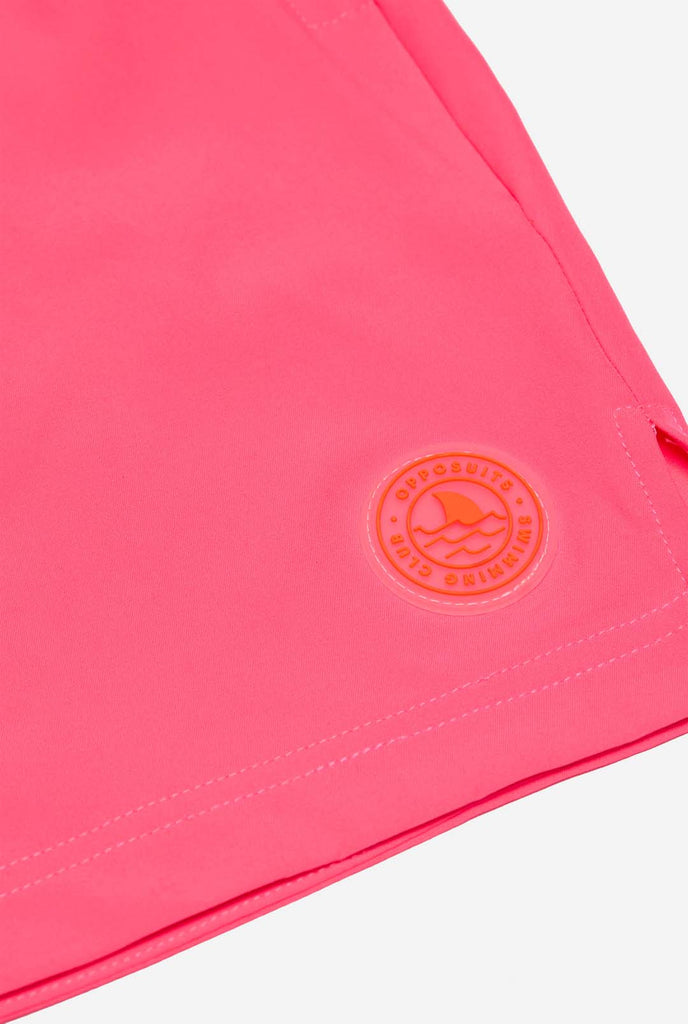 Man wearing Neon Pink Power swim trunks for men, close up