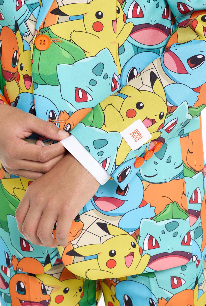 Tiener draagt ​​formeel multi-color pak met all-over Pokemon print. Het pak bevat de personages Pikachu, Bulbasaur, Charmander en Squirtle.