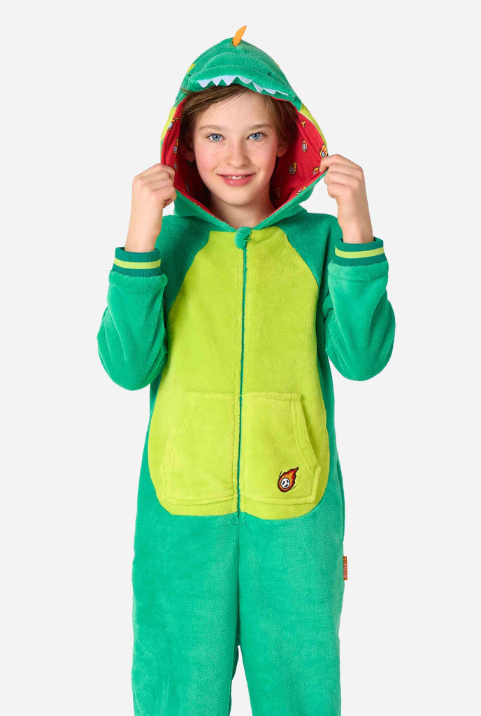 Kind draagt een groene dino onesie voor kinderen.