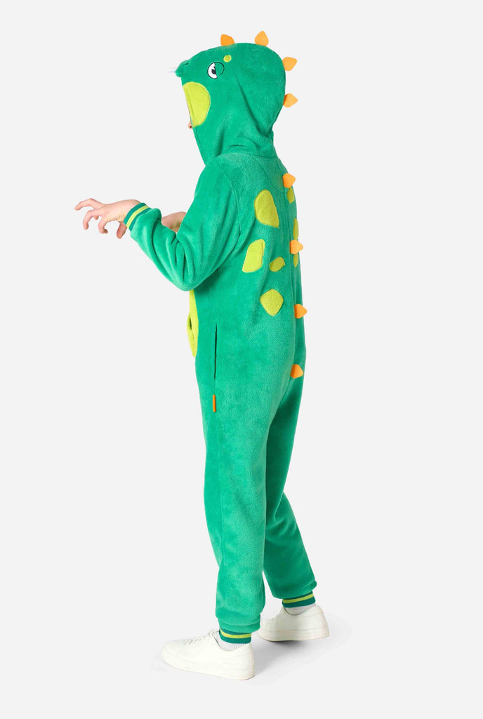 Kind draagt een groene dino onesie voor kinderen. Beeld van de zijkant.