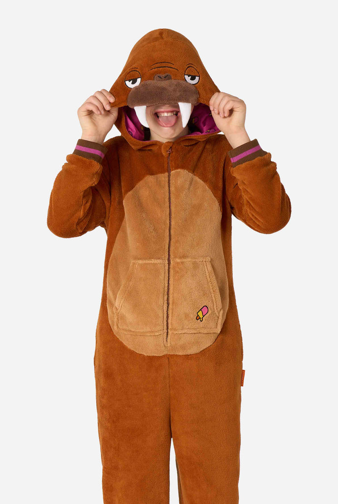 A cheerful kid wearing a brown kids onesie designed as a walrus. The onesie features a hood with fangs, stitched gloves resembling paws, and playful walrus details, perfect for cozy lounging or costume parties.