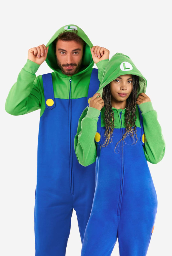 Een man en een vrouw zijn gekleed in een Luigi-thema onesie. De outfit ziet eruit als een felgroene hoodie met een "L"-symbool op de capuchon en een blauwe overall met grote gele knopen op de bandjes. Het algehele ontwerp imiteert de look van het populaire videogamepersonage Luigi, met contrasterende groene en blauwe kleuren. De achtergrond is effen, waardoor de nadruk op het kostuum ligt.