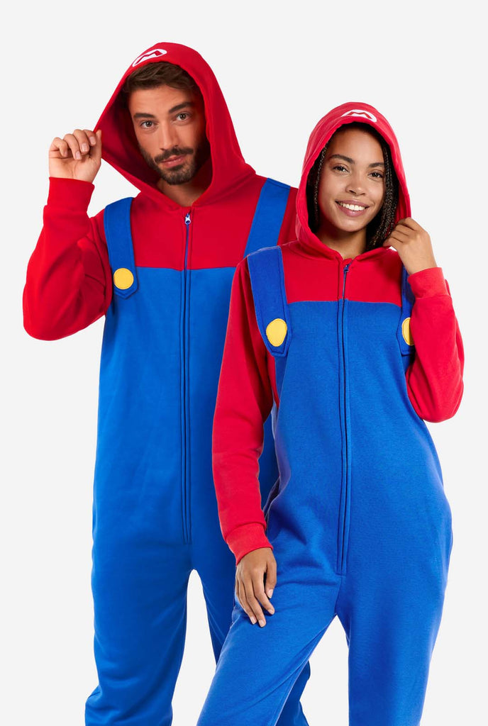 Man en vrouw dragen rood en blauw, Unisex Adult Onesie met Super Mario thema. Onesie lijkt op de Super Mario outfit.