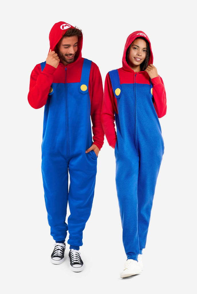 Man en vrouw dragen rood en blauw, Unisex Adult Onesie met Super Mario thema. Onesie lijkt op de Super Mario outfit. Full body image.